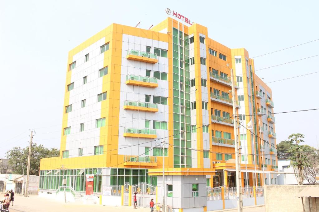un bâtiment jaune et blanc avec des personnes devant lui dans l'établissement Paradisia Hotel, à Cotonou