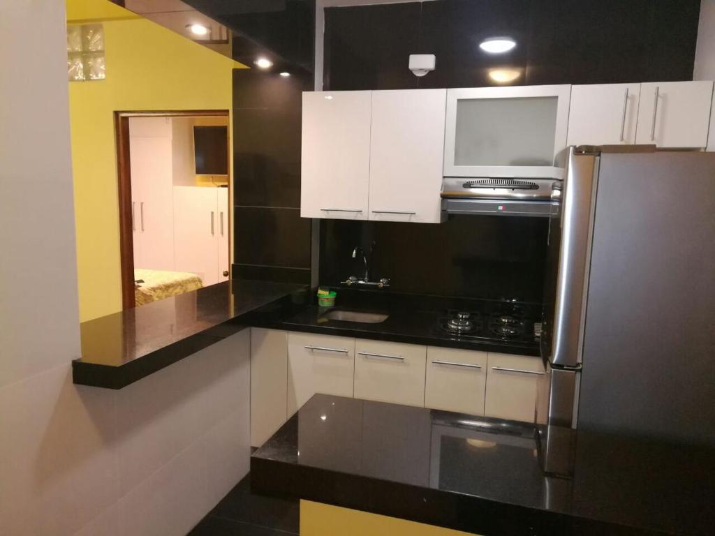 una cocina con encimeras negras y armarios blancos en Apartamento Miraflores Boulevard Tarata, en Lima