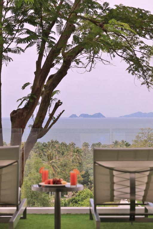 a table with a plate of food and two chairs at Code Samui Hotel in Mae Nam