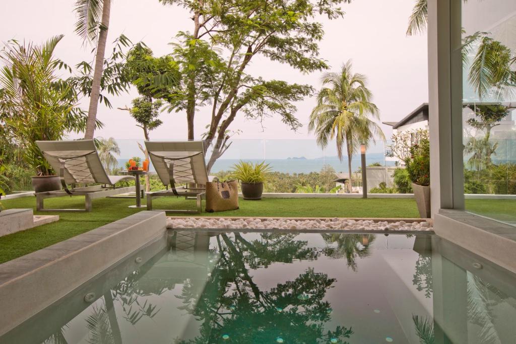 a house with a swimming pool and palm trees at Code Samui Hotel in Mae Nam