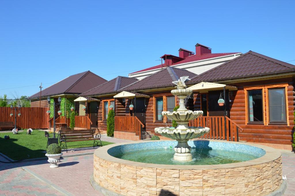 a fountain in front of a log house at Hotel Almaz in Akhtubinsk