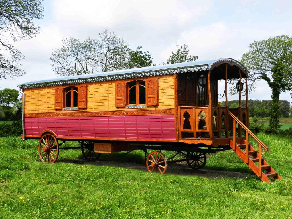 un vagón de tren de madera expuesto en un campo en Une roulotte et des chevaux, en Sulniac