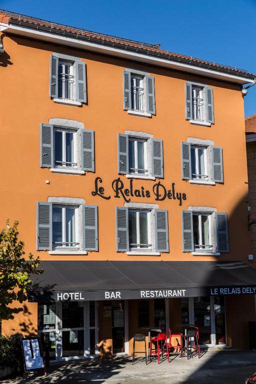 a large orange building with tables and chairs in front of it at Le Relais Délys in Saint-Rémy-sur-Durolle
