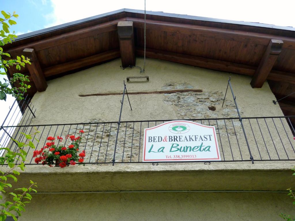 un panneau sur le côté d'un bâtiment avec des fleurs dans l'établissement La Buneta, à Macra