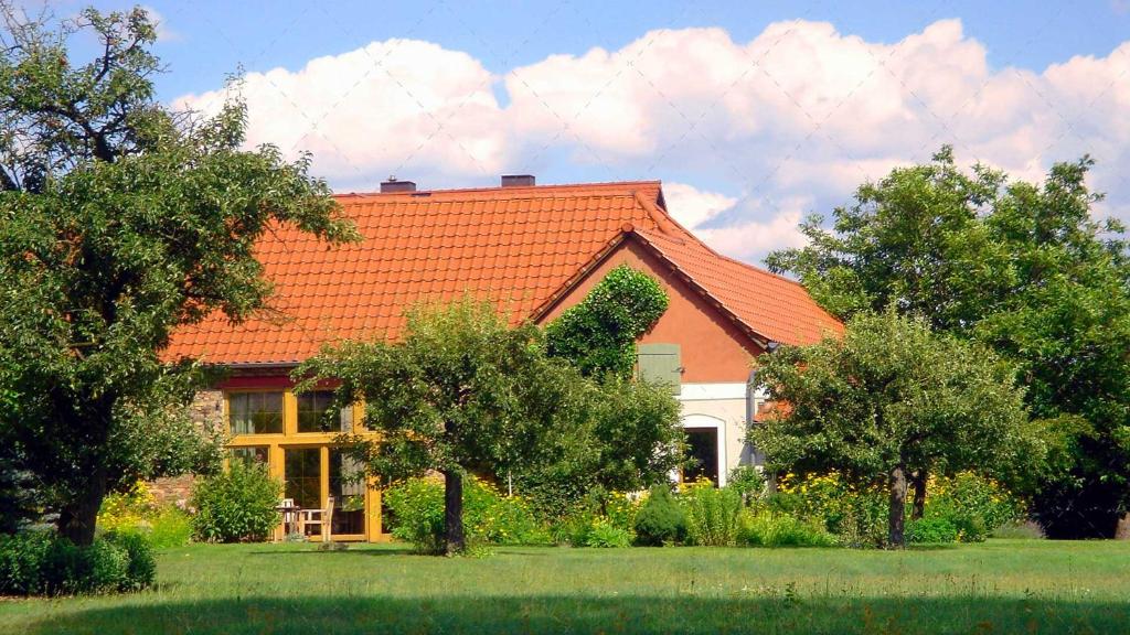 ein Haus mit einem orangenen Dach und einigen Bäumen in der Unterkunft JANISCHs Fewo im Spreewald in Neu Lübbenau