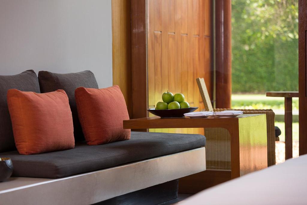 a couch with a bowl of fruit on a table at Anantara Chiang Mai Resort in Chiang Mai