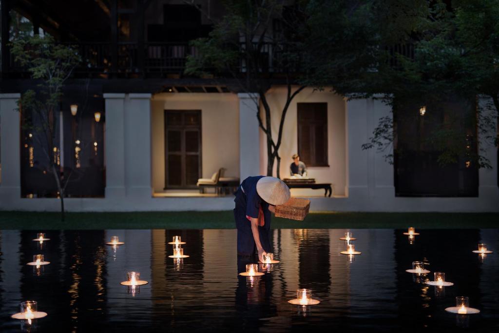 a person bending over to look at lights in the water at Anantara Chiang Mai Resort in Chiang Mai