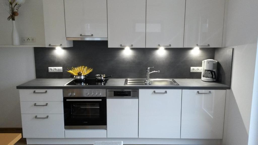 a kitchen with white cabinets and a sink at die Gartenwohnung - Tanja Tipotsch in Schwendau