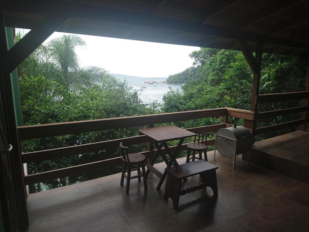 a table and chairs on a balcony with a view of the ocean at Paraíso das Tartarugas in Bombinhas