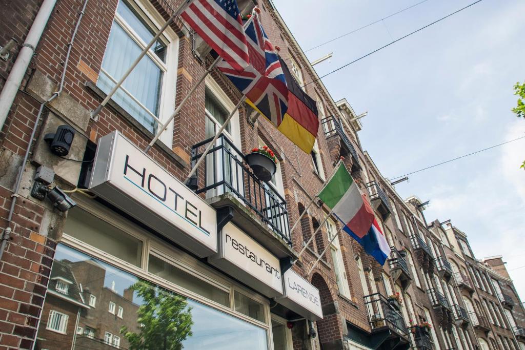 un bâtiment avec des drapeaux sur son côté dans l'établissement Hotel Larende, à Amsterdam