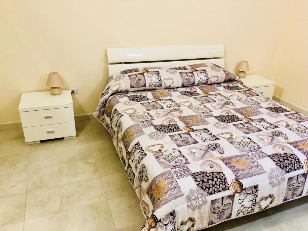 Un dormitorio con una cama con edredón y una mesita de noche. en Sogni D'oro, en Bari