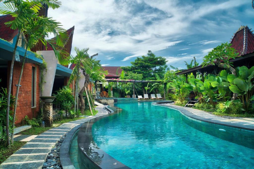 una piscina frente a una casa de agua azul en The Garden Villa, en Sanur