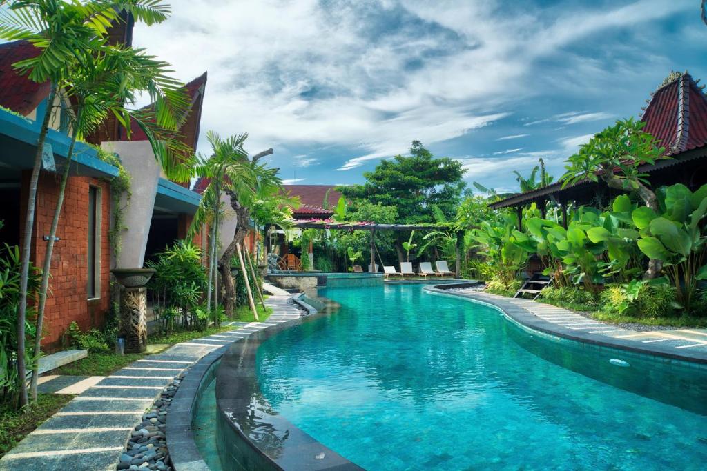 a swimming pool in front of a house with blue water at The Garden Villa in Sanur