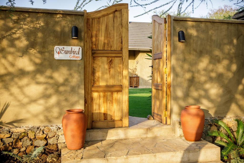 une porte en bois avec deux vases devant une maison dans l'établissement Sunbird Cottage, à Usa River