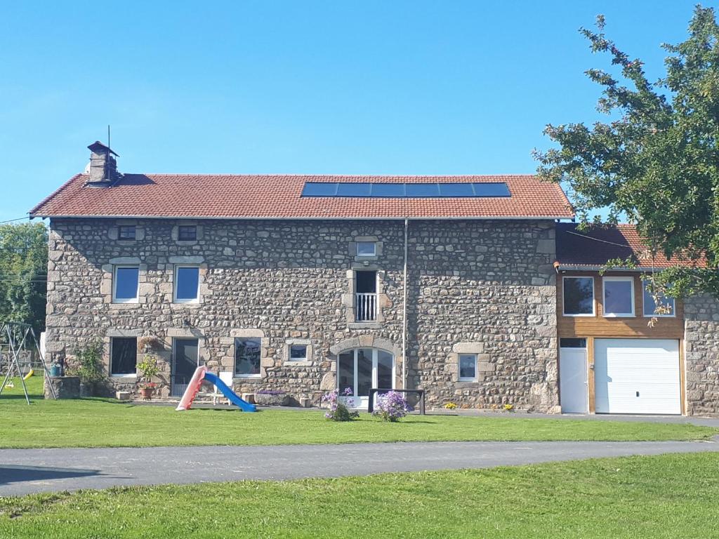 a stone house with a playground in front of it at Chez Pitch & Marina in Sauvessanges