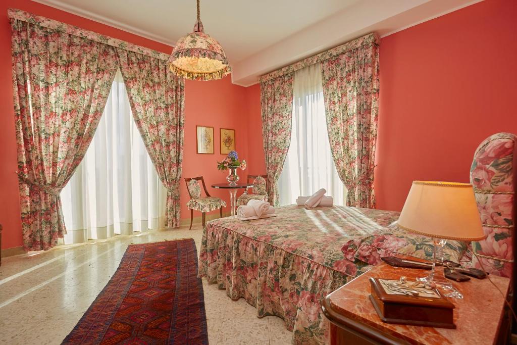a bedroom with red walls and a bed and a table at Mergellina 10 in Marsala
