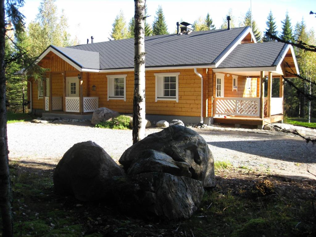 a log cabin with a large rock in front of it at Kuusitorppa in Varpaisjärvi