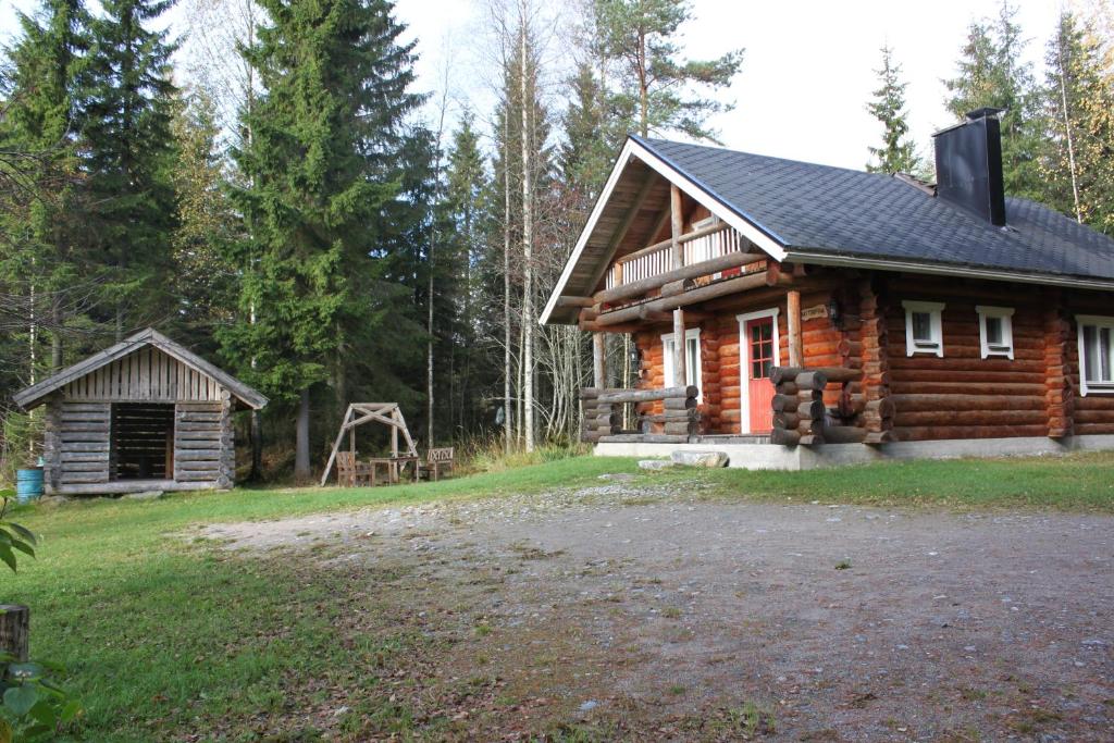 Mäkitorppa في Varpaisjärvi: كابينة خشب في الغابة مع ساحة