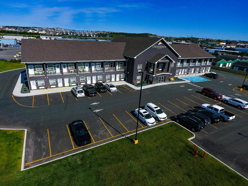 un grand bâtiment avec des voitures garées dans un parking dans l'établissement Crossroads Inn & Suites, à Saint-Jean