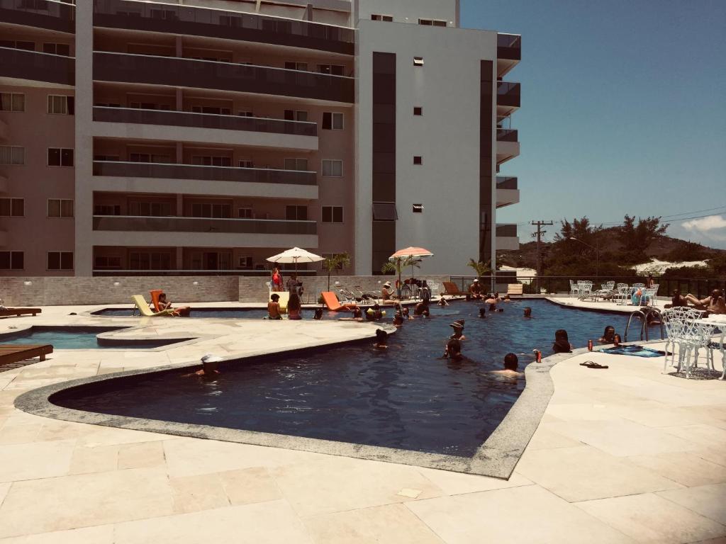 een groep mensen in een zwembad in de buurt van een gebouw bij Arraial do Cabo - Melhor da Pr Grande Le Bon 405B in Arraial do Cabo