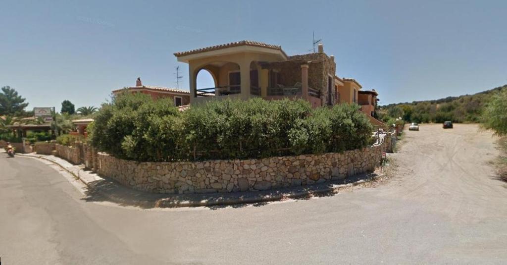 a house with a stone wall next to a road at Appartamento Simius in Villasimius