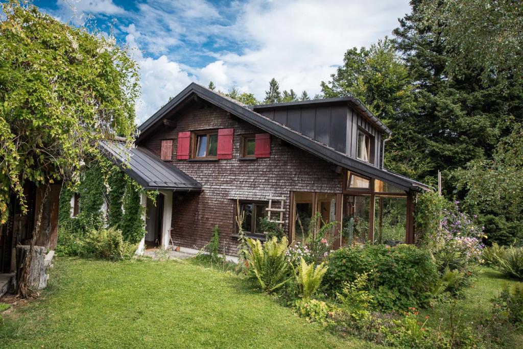 una antigua casa de ladrillo con ventanas rojas y un patio en Ferienhaus Bergblick, en Schwarzenberg im Bregenzerwald