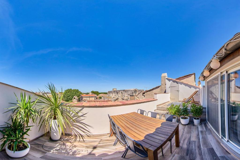 eine Terrasse mit einem Holztisch und Topfpflanzen in der Unterkunft Truchet Penthouse in Arles