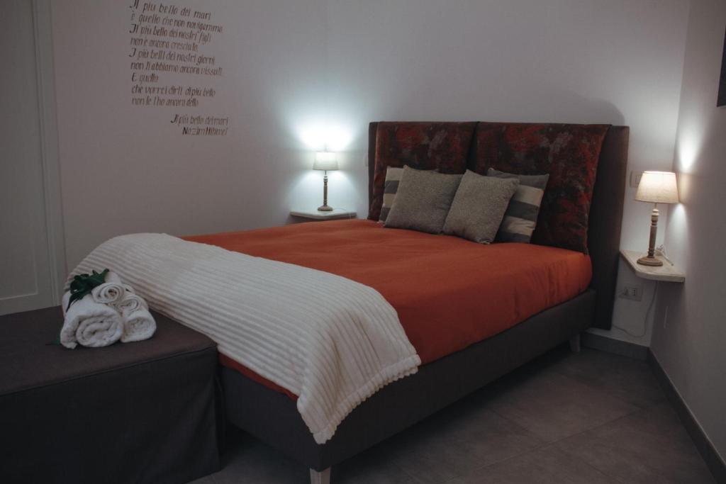 um quarto com uma cama grande com lençóis e almofadas laranja em Vico sferracavalli em Lecce
