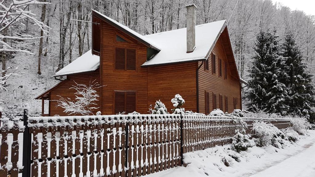 a wooden church with a fence in the snow at Krókusz Kulcsosház - Boga in Boga