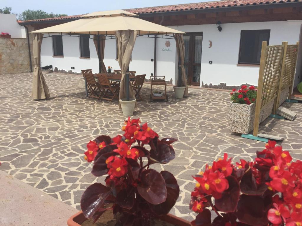 a patio with red flowers and an umbrella at Casa Bice - IUN P4163 in Alghero