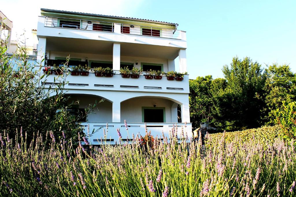 a white building with flower boxes on it at Apartments Frgacic in Baška