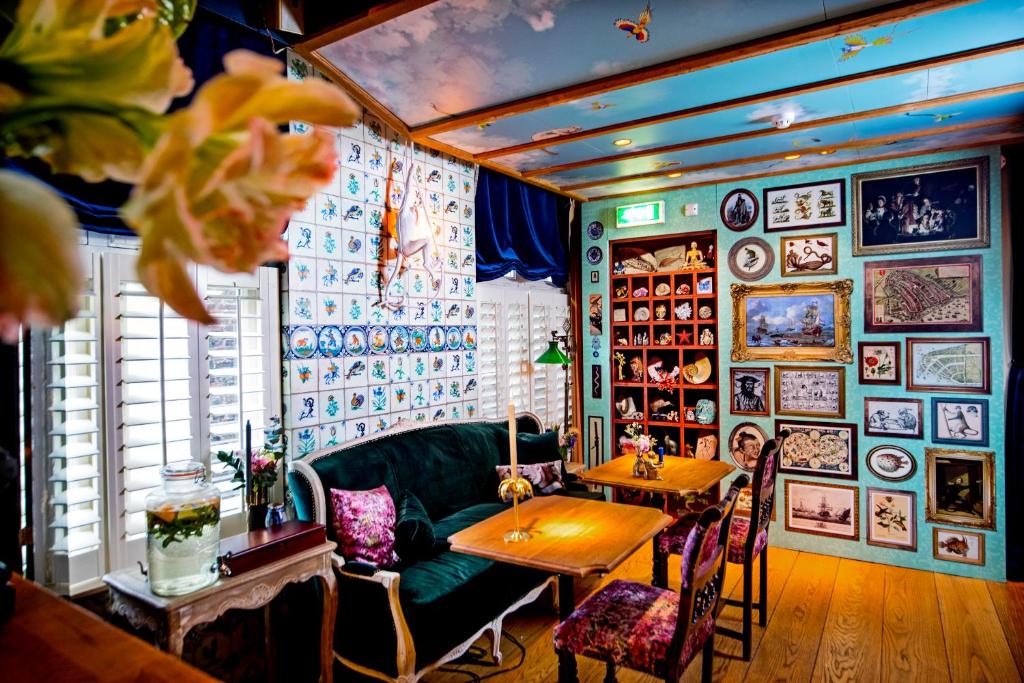 Habitación con sofá verde, mesas y cuadros en la pared. en Rosalia's Menagerie Cocktail bar & InnUpstairs, en Ámsterdam