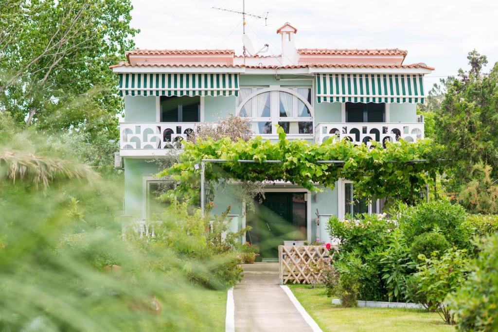 a white house with a garden in front of it at San Antonio Beach Apartments in Potos
