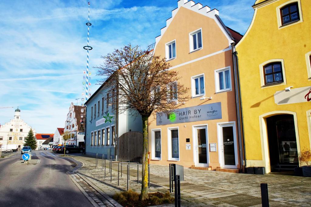 un edificio giallo su una strada con un albero di fronte di Boardinghouse Gaimersheim a Gaimersheim