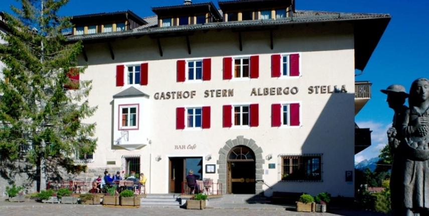 a large white building with red shutters on it at Hotel Gasthof Stern in Nova Ponente