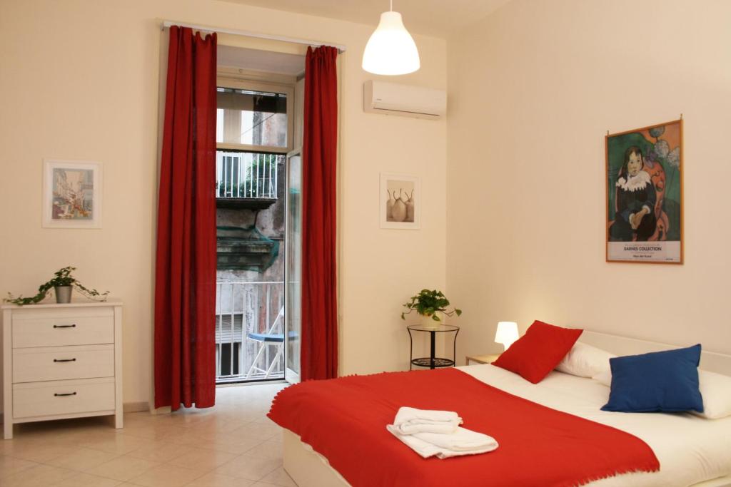ナポリにあるcasa grecaのベッドルーム1室(赤いカーテンと窓付きのベッド1台付)