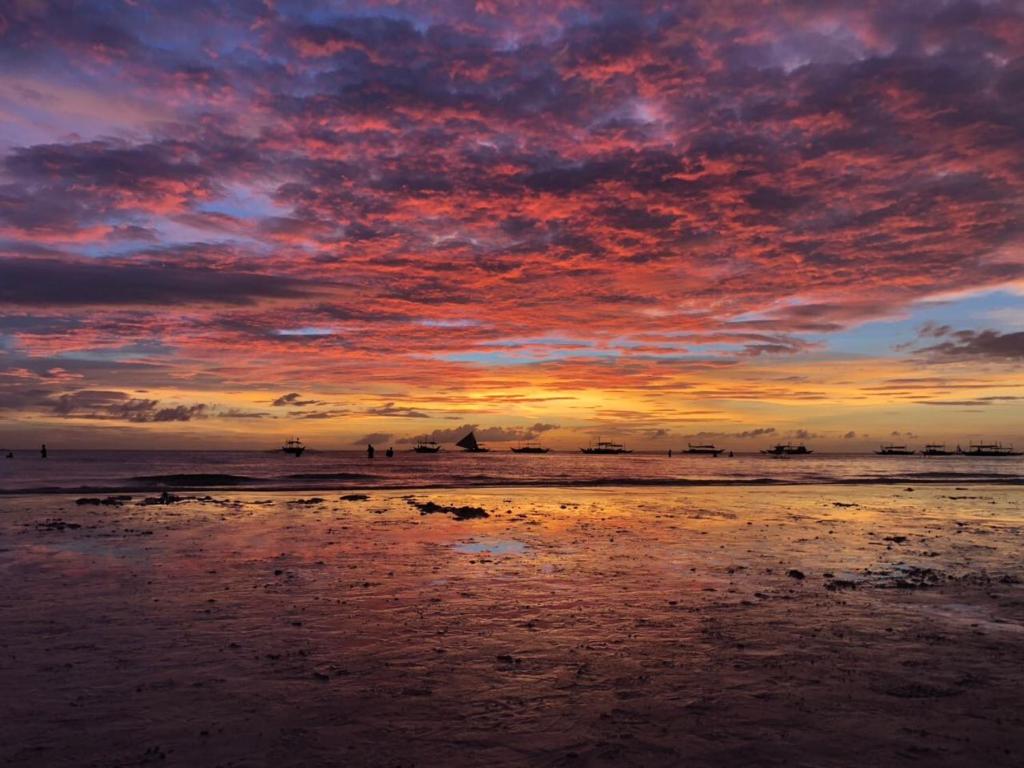 a sunset on a beach with people in the water at Oceanside Studio in Daytona Beach Shores