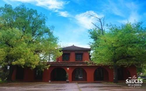 czerwony budynek z drzewami przed nim w obiekcie Quinta en Pilar w mieście Del Viso