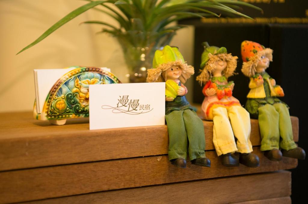 a group of figurines sitting on a shelf with a sign at Slower Life B&B in Jiaoxi