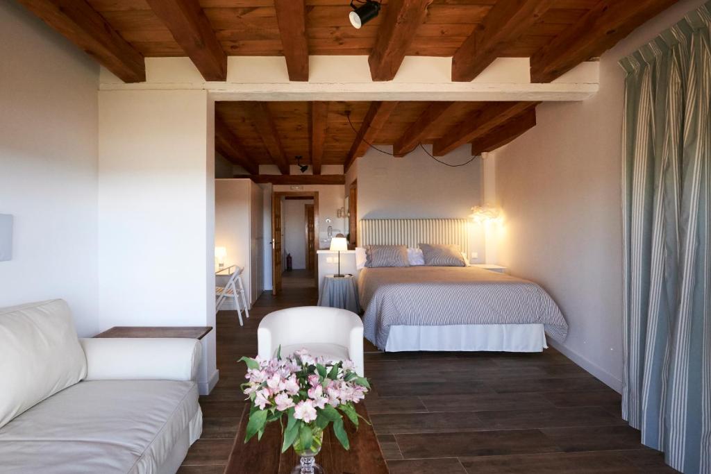 a bedroom with two beds and a couch and flowers on a table at Casa Rural Victoriano Pedraza in Rades de Abajo