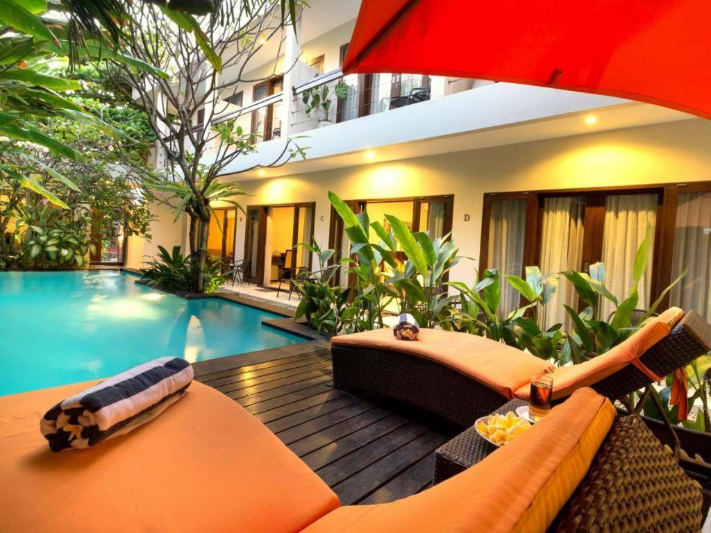 a living room with a couch and an umbrella and a pool at The Pavilion Hotel Kuta in Kuta