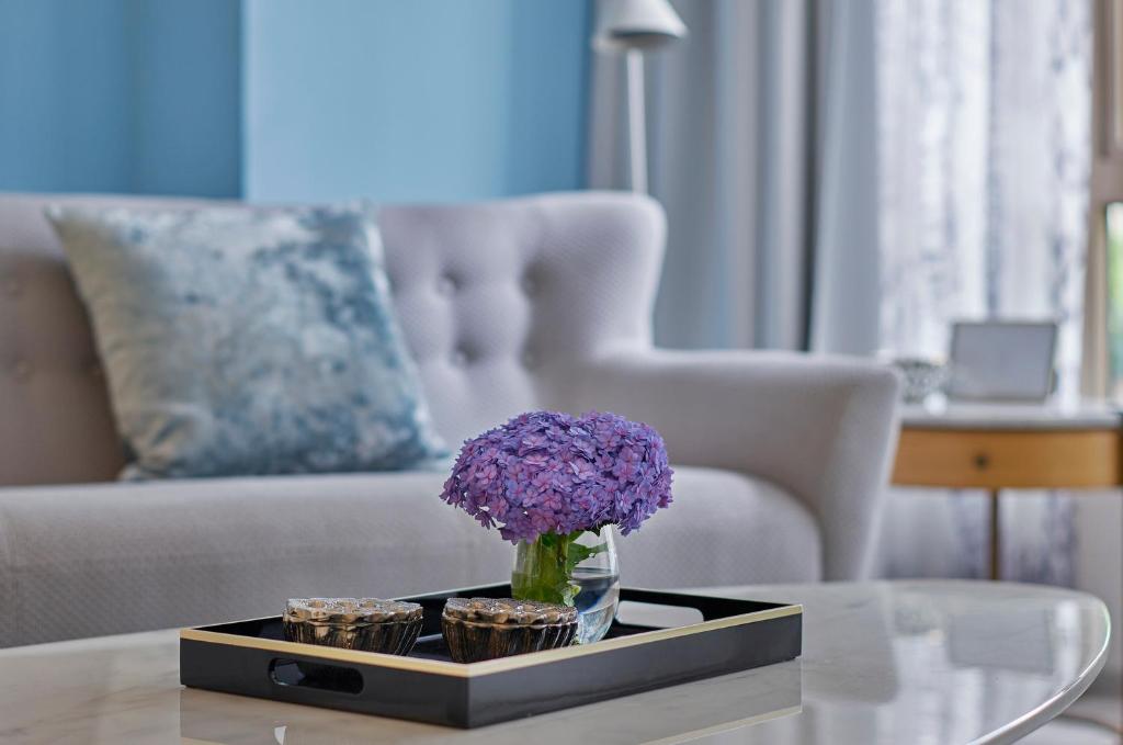 a living room with a table with a vase of purple flowers at Lanson Place Winsland, Singapore in Singapore