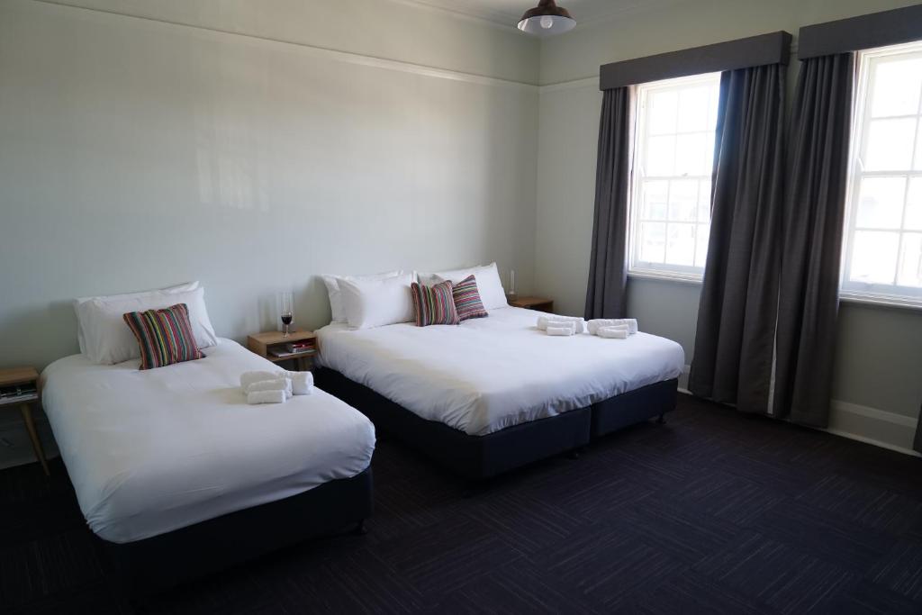 two beds in a room with two windows at Rosehill Hotel in Sydney