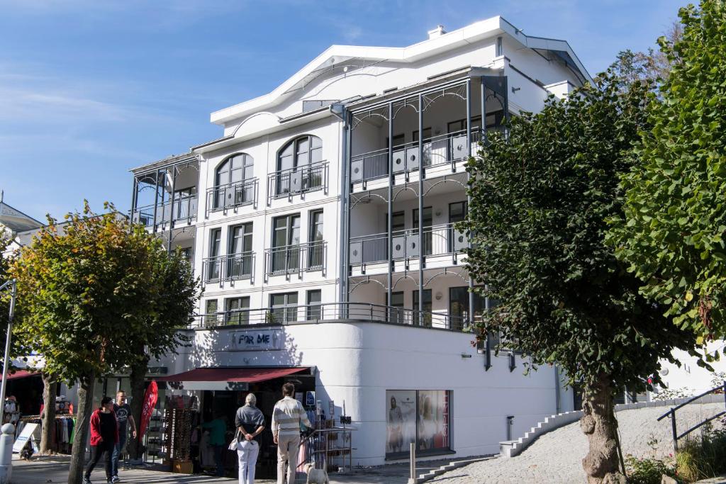Biały budynek z ludźmi stojącymi przed nim w obiekcie Villa Louisa - Wohnung 51 w mieście Sellin