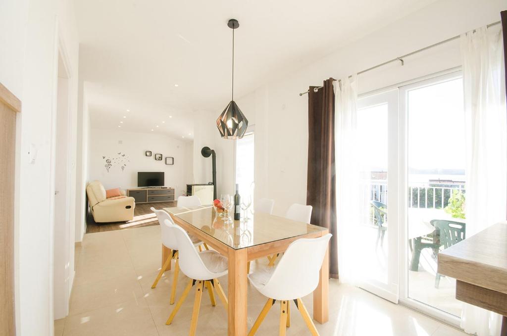 a dining room with a table and white chairs at Apartman Korina in Sukošan