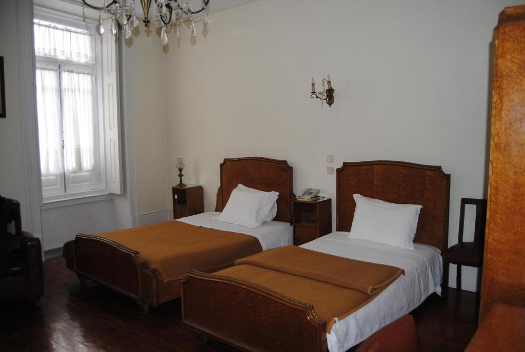 1 Schlafzimmer mit 2 Betten und einem Kronleuchter in der Unterkunft Hotel Peninsular- Porto in Porto
