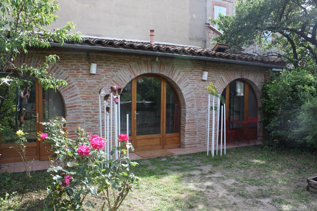 une maison en briques avec une porte en bois et des fleurs dans l'établissement Le Merle Rose, à Toulouse