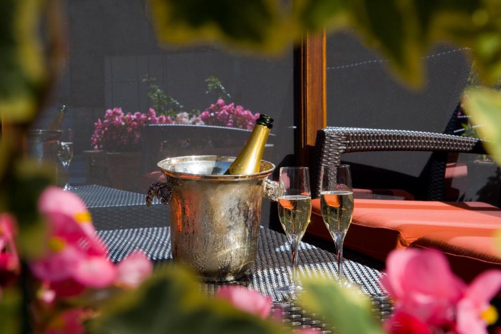 Una botella de champán en un cubo sobre una mesa con dos copas. en Nicey - Hôtel Spa, Lounge, Coworking en Romilly-sur-Seine