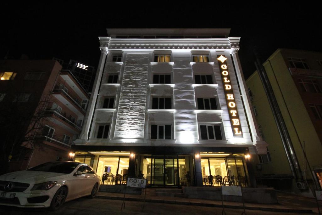 een witte auto geparkeerd voor een gebouw bij Ankara Gold Hotel in Ankara
