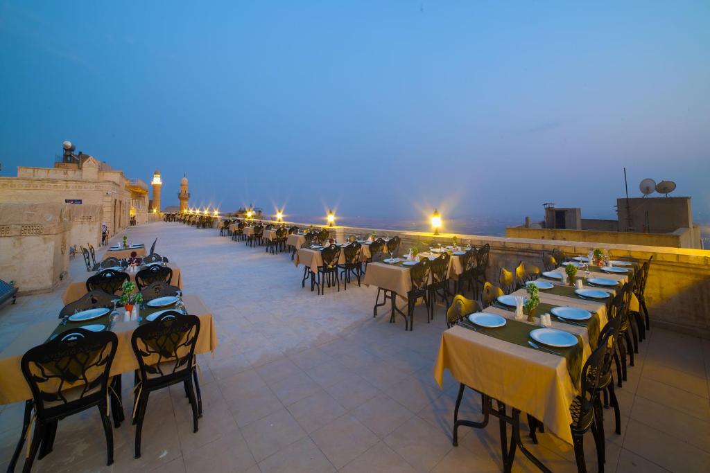a row of tables and chairs on a balcony at night at Kaya Ninova Hotel in Mardin